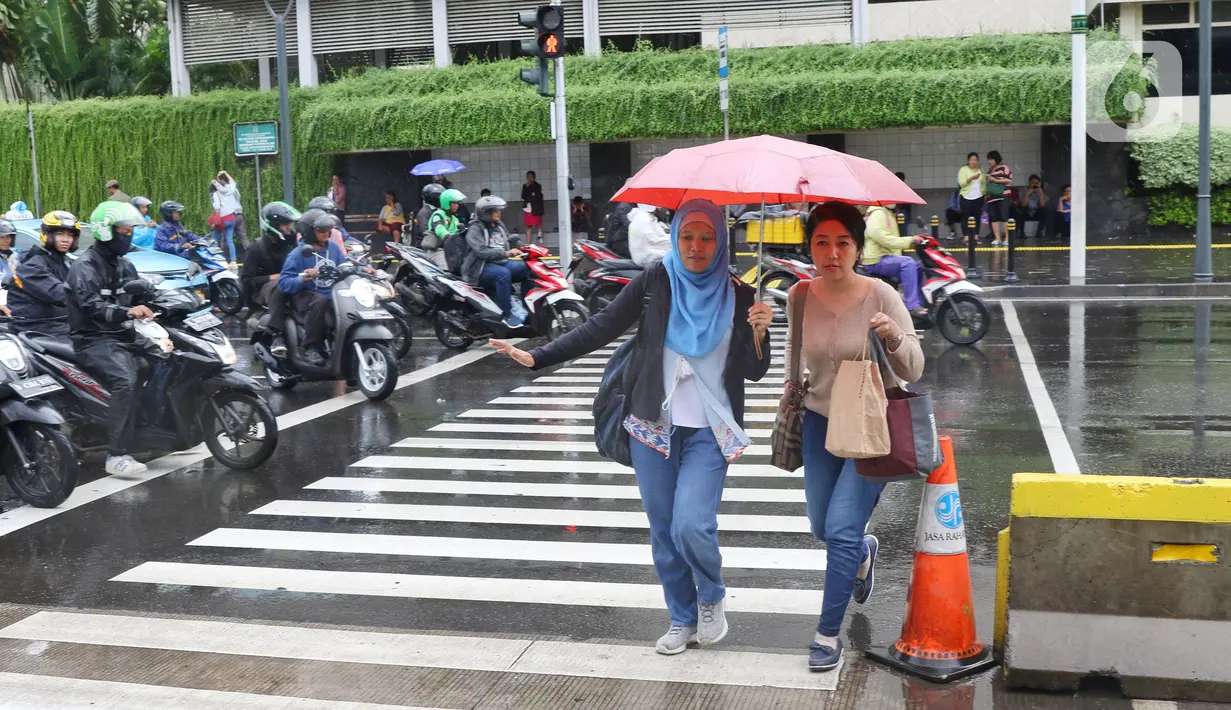 Pejalan kaki melintas menggunakan payung saat hujan mengguyur kawasan Jakarta, Senin (3/2/2020). Badan Meteorologi, Klimatologi, dan Geofisika (BMKG) merilis informasi peringatan dini cuaca ekstrem yang diperkirakan berlangsung hingga Rabu (5/2/2020) mendatang. (Liputan6.com/Angga Yuniar)