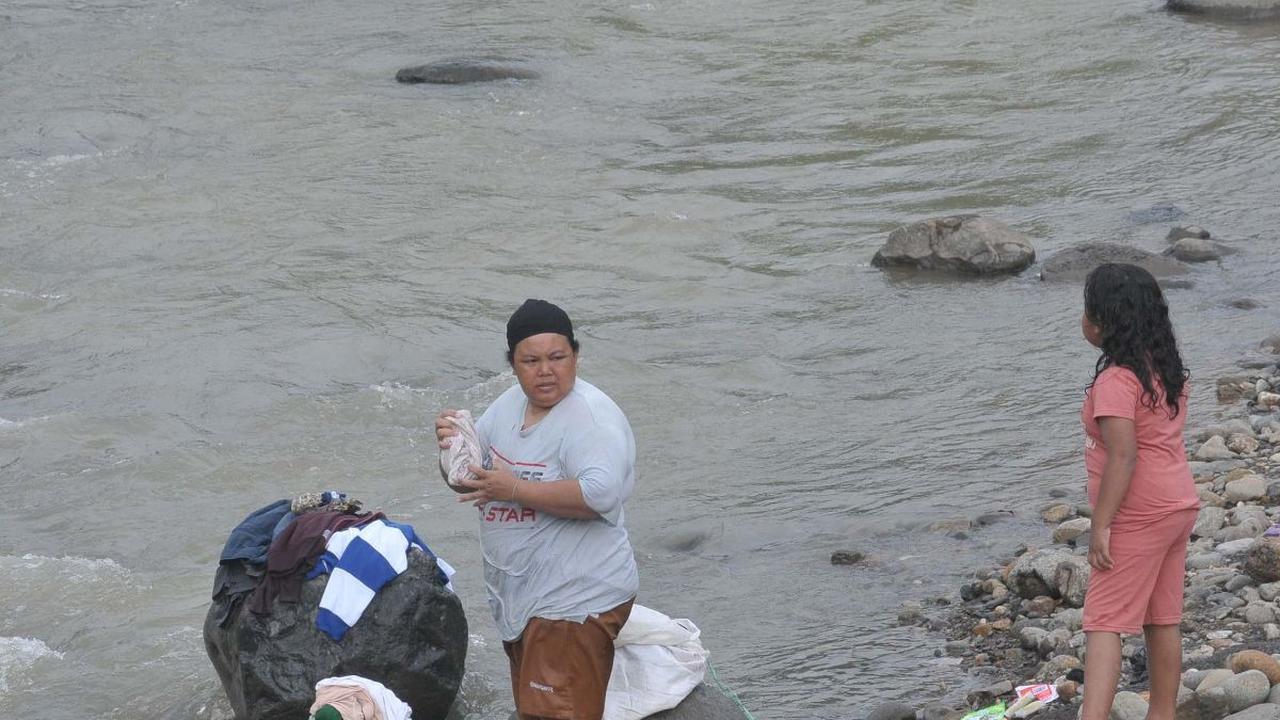 Warga mencuci pakaian di aliran kali Desa Pabuaran, Citeureup, Kabupaten Bogor, Jawa Barat, Jumat (24/5/2024). Sumur-sumur milik warga Desa Pabuaran mulai mengalami kekeringan.&nbsp;Foto: Merdeka.com/Imam Buhori