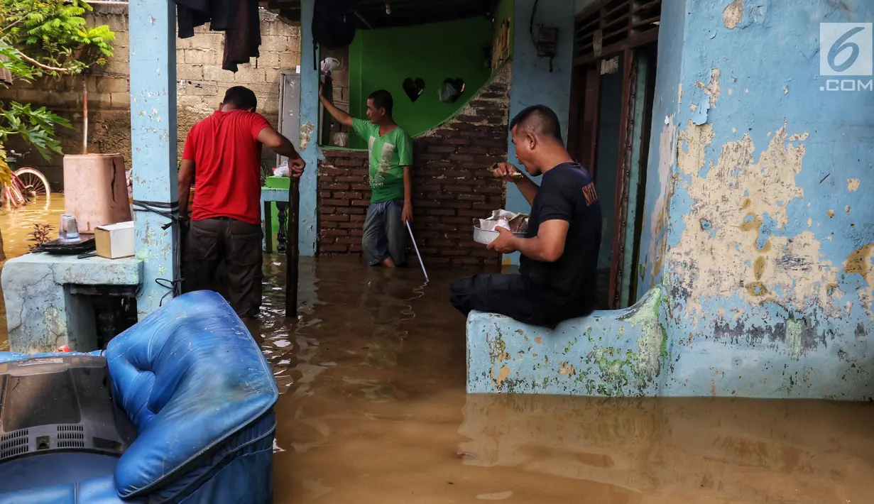 Warga membersihka rumahnya yang terendam banjir di kawasan bantaran kali Cisadane, Tangerang, Jumat (26/4). Banjir kiriman setinggi 2 meter sempat melanda kawasan akibat curah hujan yang tinggi di bogor membuat derasnya air mengalir jauh sampai ke tempat ini. (Liputan6.com/Johan Tallo)