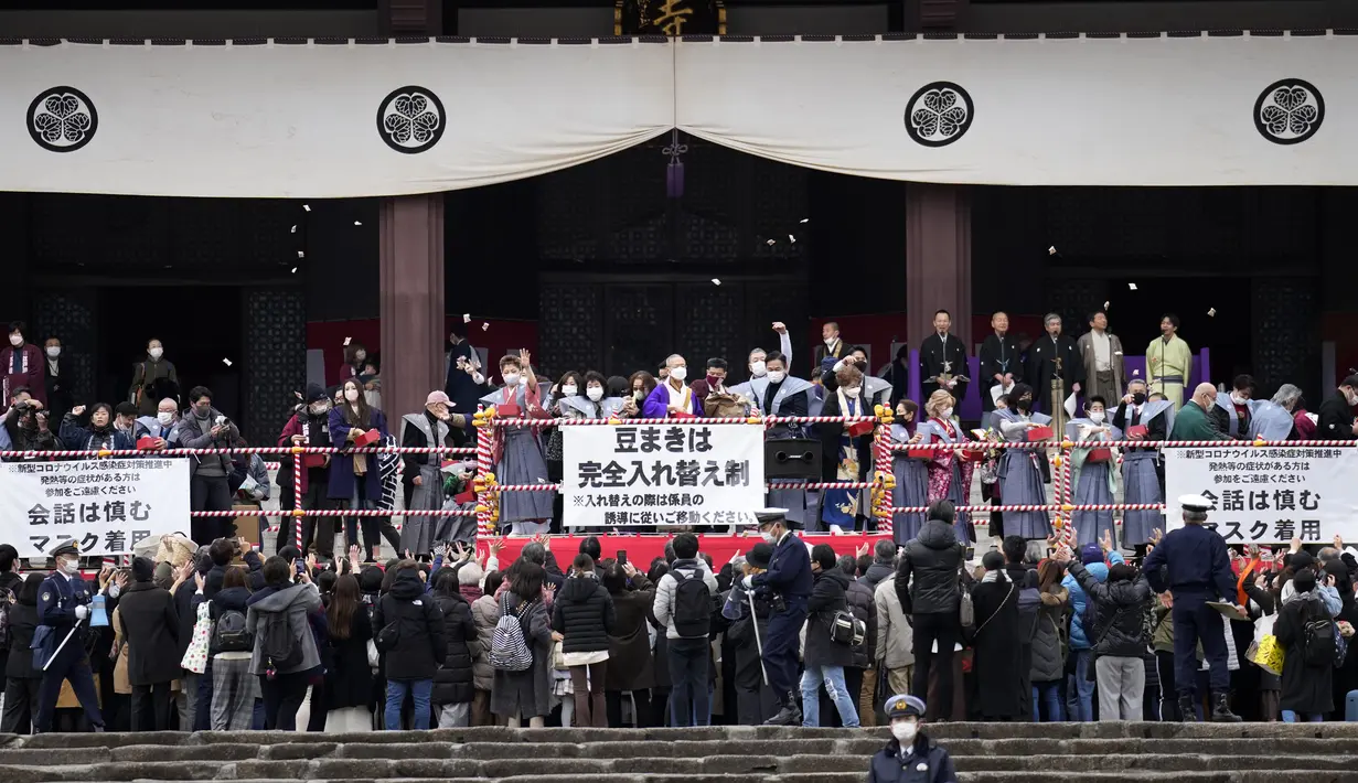 Orang-orang mencoba menangkap kacang keberuntungan yang disebarkan selama "Mame-maki", upacara melempar kacang, di kuil Buddha Zojoji, Tokyo, Jumat (3/2/2023). Selain dirayakan di rumah bersama keluarga, tradisi Mame-maki ini juga dilakukan di sekolah. Kadang kala dilaksanakan di tempat umum, seperti di pusat perbelanjaan atau di kuil.  (AP Photo/Eugene Hoshiko)