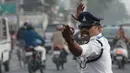 Polisi lalu lintas India Ranjeet Singh melakukan gerakan seperti tarian saat mengarahkan lalu lintas di persimpangan Indore, India (22/12). (AFP Photo/Indranil Mukherjee)