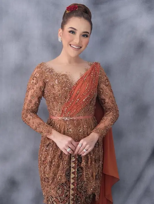 Saat hari-H pernikahan Syifa, Ayu Ting Ting mengenakan kebaya warna teracota. Detail kerah v-neck membuat lehernya terlihat lebih jenjang. Ditambah, aksen selendang di bahu dan taburan beads yang membuat penampilan Ayu semakin elegan. [@ayutingting92]