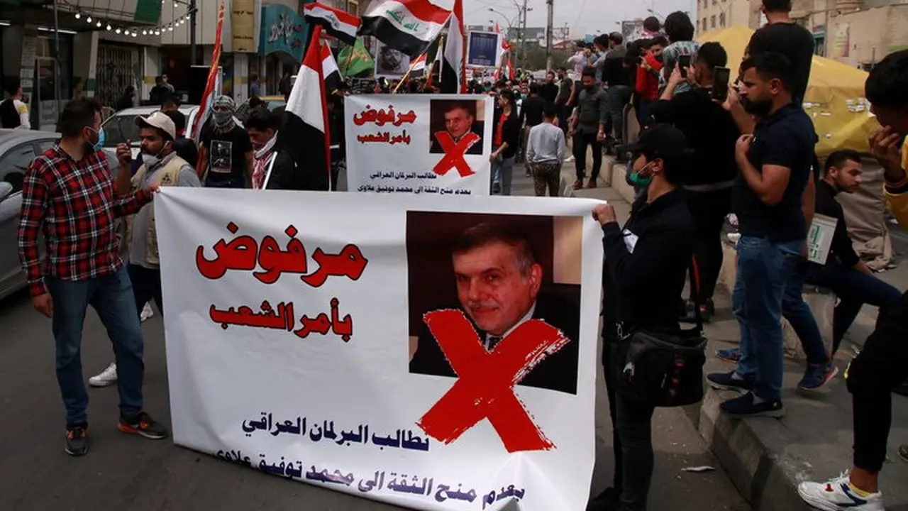 Pengunjuk rasa memegang poster yang menunjukkan Perdana Menteri Irak yang ditunjuk Mohammed Tawfiq Allawi dengan bahasa Arab yang berbunyi, "Ditolak atas perintah rakyat," dalam sebuah rapat umum di Baghdad, Irak, Minggu, 1 Maret 2020.