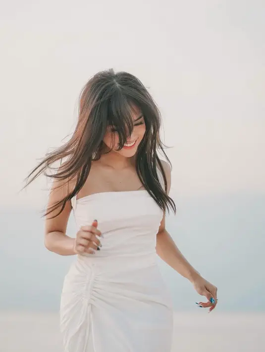 Main di pantai dengan gaya cantik ala Fuji pakai halter-dress putih. Dress ini memiliki detail kerut cantik di salah satu bagian pinggang. [Foto: Instagram/fuji_an]