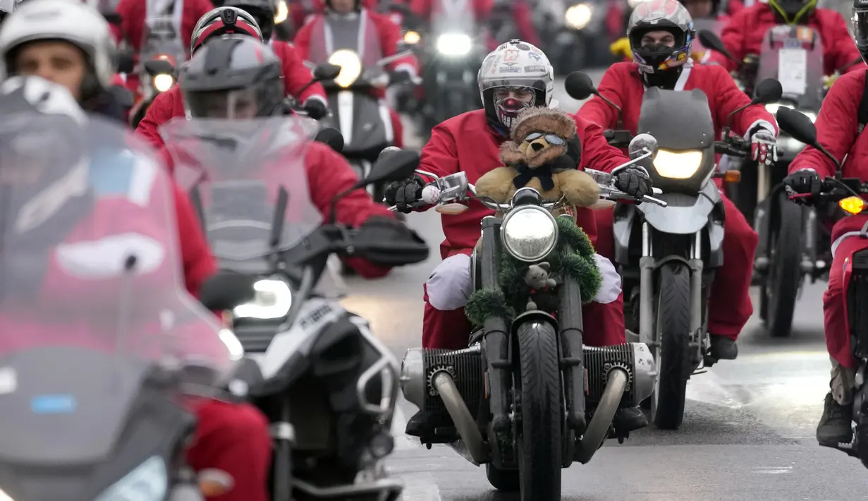 Pengendara sepeda motor yang mengenakan kostum Sinterklas mengendarai motor mereka selama parade Sinterklas di Beograd, Serbia, Minggu (26/12/2021). Mereka melakukan konvoi menuju rumah sakit anak-anak untuk membagikan mainan hadiah Natal kepada pasien di sana. (AP Photo/Darko Vojinovic)