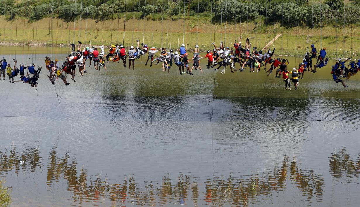 Sejumlah orang bergelantungan dengan tali usai melompat dari jembatan berketinggian 30 meter di Hortolandia, Brasil, Minggu (10/4). Sebanyak 149 orang mencoba membuat rekor dunia dengan melompat bersama dari atas jembatan. (REUTERS/Paulo Whitaker)
