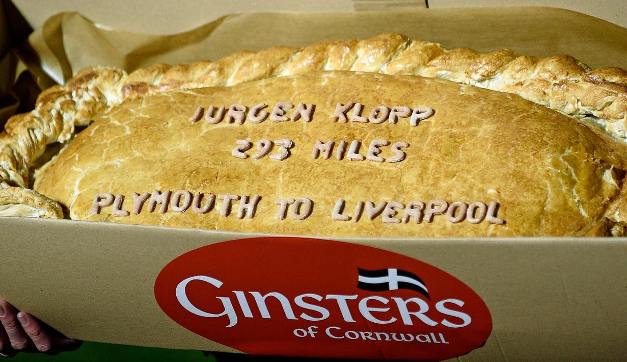 Sindiran pada Jurgen Klopp berupa kue pastel raksasa yang bertuliskan jarak tempuh Liverpool menuju Plymouth. (EPA/Gerry Penny)