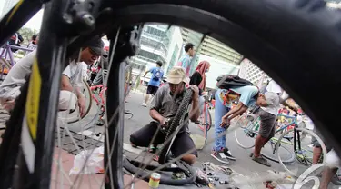 Seorang teknisi sepeda sedang memperbaiki roda sepeda salah seorang pengunjung  di kawasan Bundaran Hotel Indonesia, Jakarta, Minggu (14/12/2014). (Liputan6.com/Faizal Fanani)