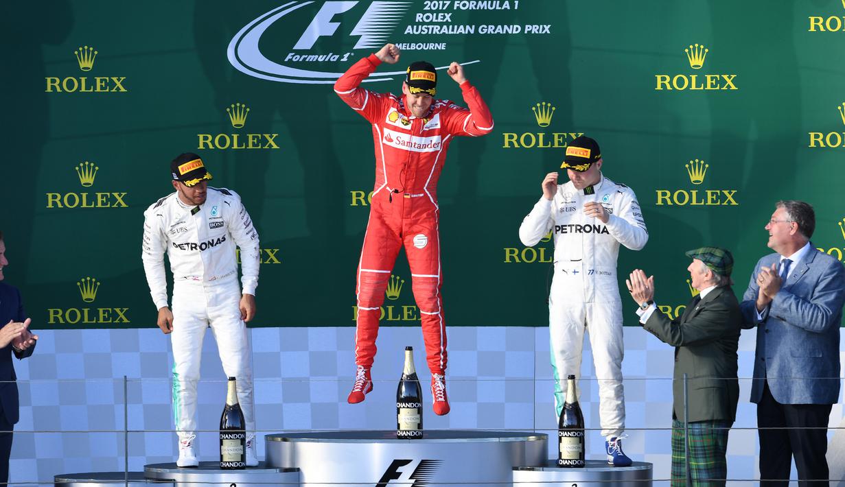 Pembalap Ferrari, Sebastian Vettel melompat merayakan kemenangannya di atas podium balapan GP Australia di Sirkuit Albert Park, Melbourne, Minggu (26/3). Ini merupakan kemenangan pertama Vettel bersama Ferrari sejak GP Singapura 2015. (WILLIAM WEST/AFP)