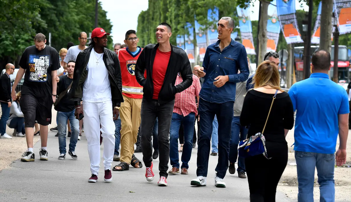 Sejumlah pria tertinggi di dunia berjalan di tengah keramaian di Champs-Elysees Avenue, Paris, 1 Juni 2018. Belasan pria tertinggi di dunia bertemu pada akhir pekan di ibu kota Prancis. (AFP/GERARD JULIEN)