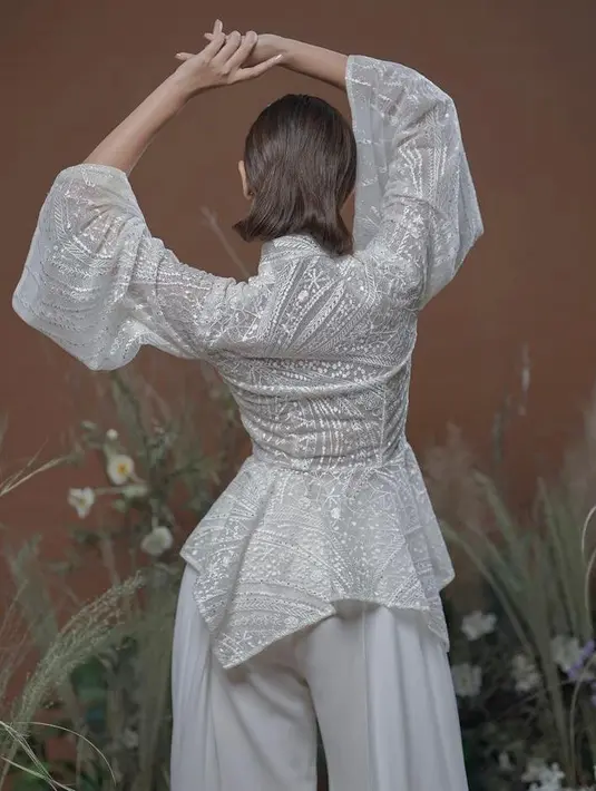 Di look kedua ini, Sheila mengenakan atasan putih dengan model cheongsam berlengan lebar dan detail peplum. (Instagram/willymulyadi27).