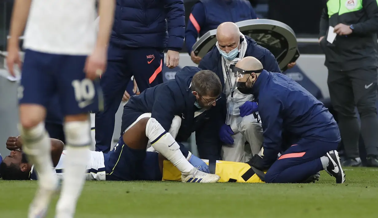 Gelandang Tottenham Hotspur, Japhet Tanganga mendapat perawatan medis usai mengalami cedera saat menghadapi Aston Villa dalam laga lanjutan Liga Inggris 2020/2021 pekan ke-37 di Tottenham Hotspur Stadium, Rabu (19/5/2021). Tottenham kalah 1-2 dari Aston Villa . (AP/Paul Childs/Pool)