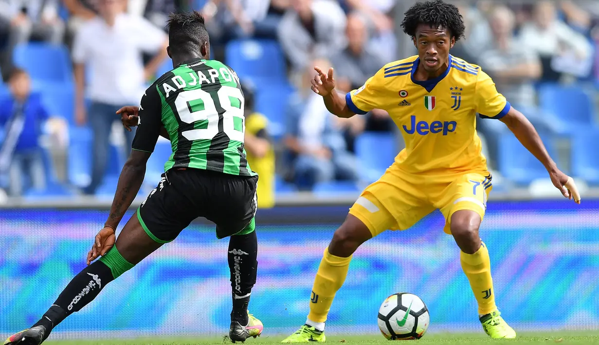 Pemain Sassuolo, Claud Adjapong (kiri) mencoba merebut bola dari pemain Juventus, Juan Cuadrado pada lanjutan Serie A di  Stadio Citta del Tricolore, Reggio Emilia, Italia (17/9/2017). Juventus menang 3-1. (AFP/Marco Bertorello)