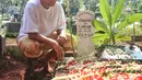 Duduk jongkok di samping nisan sang ayah setelah prosesi pemakaman selesai. Usai pemakaman, Ibnu menceritakan sang ayah meninggal karena penyakit komplikasi. [Foto: Adrian Putra/Fimela.com]