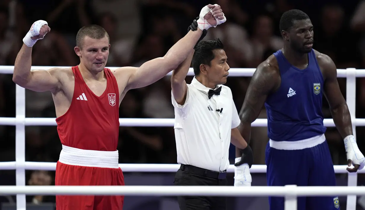 Wasit Indonesia, Muhammad Arisa Putra Pohan saat memimpin pertandingan semifinal tinju Olimpiade Paris 2024 antara petinju Ukraina, Oleksandr Khyzhniak (kiri) melawan petinju Brasil, Wanderley De Souza di North Paris Arena, Villepinte, Prancis, Jumat (02/08/2024). (AP Photo/John Locher)