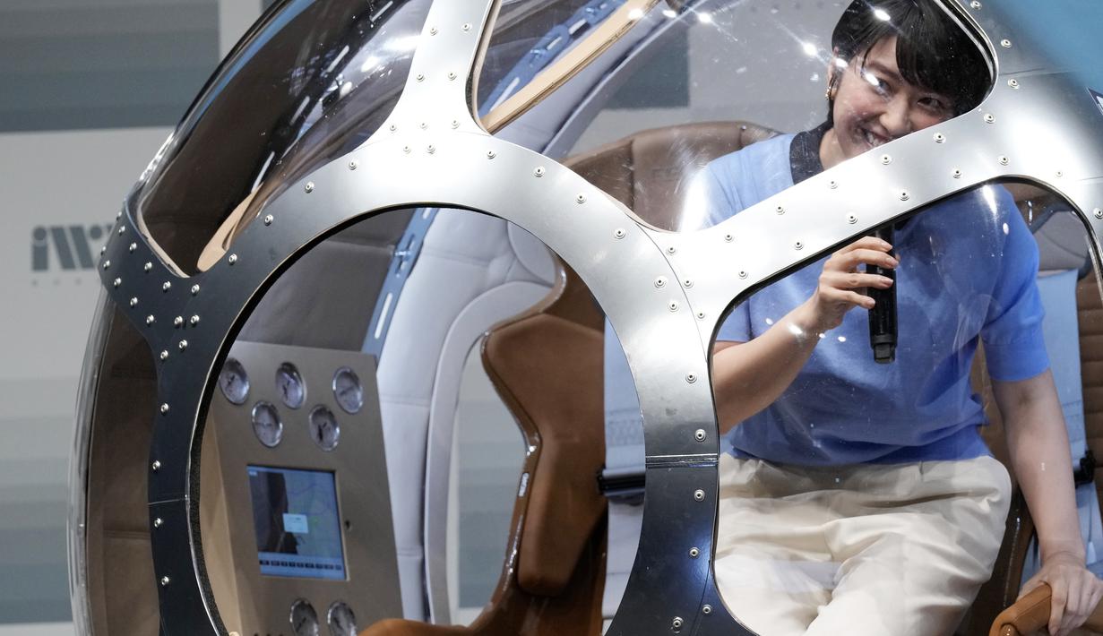 Entertainer Jepang Arisa Kuroda menaiki kabin dua tempat duduk yang menurut perusahaan rintisan mampu terbang hingga ketinggian 15 mil, kira-kira di tengah stratosfer, saat konferensi pers di Tokyo, Selasa, 21 Februari 2023. Perusahaan startup Jepang mengumumkan rencana Selasa untuk meluncurkan penerbangan balon pengamatan ruang angkasa komersial yang diharapkan akan membawa pengalaman yang sangat mahal ke bumi. (Foto AP/Eugene Hoshiko)