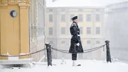 Seorang penjaga kerajaan berdiri saat salju turun di luar Royal Castle di Stockholm, Swedia (28/1/2021). Salju turun sekitar lima hingga sepuluh sentimeter diperkirakan akan turun - atau bahkan hingga 15 sentimeter di bagian pesisir di wilayah timur laut Uppsala. (Henrik Montgomery/TT via AP)