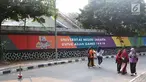 Mahasiswa melintas di depan mural bertema Asian Games 2018 di kawasan Universitas Negeri Jakarta, Kamis (16/8). Mural karya mahasiswa seni rupa tersebut dibuat dalam rangka menyambut Asian Games 2018. (Liputan6.com/Immanuel Antonius)