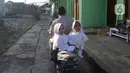 Kembar siam Al Dewi Putri Ningsih (9) dan Al Putri Anugrah (9) dibonceng sang ayah Iwan Kurniawan (43) menuju sekolah mereka di kawasan Sucinaraja, Garut, Jawa Barat, Senin (22/5/2023). (merdeka.com/Arie Basuki)