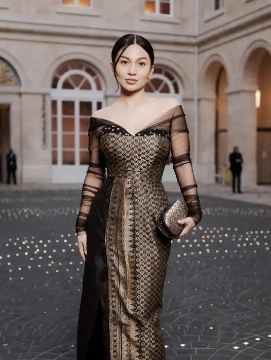 Ariel Tatum dibalut sebuah dress off-the-shoulder bernuansa kehitaman dari kain tenun yang memiliki sentuhan warna emas yang mewah. [Foto: Instagram/arieltatum]