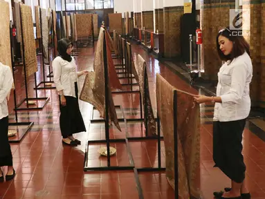 Sejumlah pengunjung melihat kain batik di Musium Bank Mandiri, Jakarta, Rabu (25/10). Pameran batik 100 kain negeri tersebut merupakan karya desainer Oscar Lawalata. (Liputan6.com/Angga Yuniar)