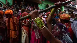 Sejumlah wanita memukul pria dengan tongkat (lathi) selama perayaan Lathmar Holi di Barsana di Mathura, India, (24/2). Lathmar Holi adalah perayaan lokal festival Hindu Holi, biasanya beberapa hari sebelum festival Holi. (AFP Photo/Dominique Faget)