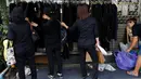 Warga membeli baju hitam untuk dikenakan selama masa berkabung atas wafatnya raja Bhumibol Adulyadej di Grand Palace di Bangkok, Thailand (17/10). Penduduk Bangkok mengenakan pakaian hitam sebagai tanda berduka kepergian raja mereka. (Reuters/Issei Kato)