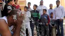 Karim Hussein mengusap wajahnya dengan pecahan kaca saat unjuk kebolehan di Kairo (18/3/2016). Warga sekitar tampak menonton aksi mengerikan dari Karim Hussein "The Pharaoh"  (Reuters/ Mohamed Abd El Ghany)