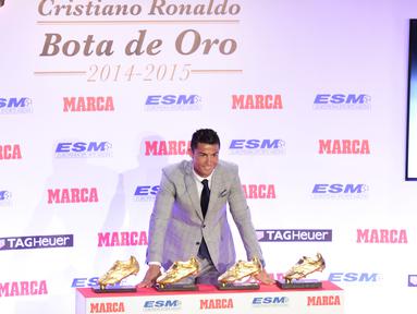 Penyerang Real Madrid, Cristiano Ronaldo berpose di depan empat sepatu emas miliknya di Madrid, Spanyol, Selasa (13/10). Ronaldo kembali menerima Golden Boot dan merupakan gelar keempat bagi dirinya setelah mencetak 48 gol. (AFP PHOTO/JAVIER Soriano)