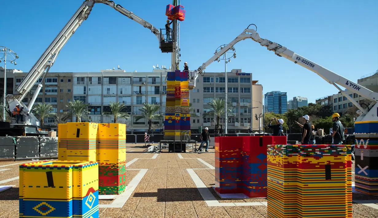 Pekerja dan relawan menyusun kepingan LEGO untuk membuat menara di Lapangan Rabin di Tel Aviv, Israel, Rabu (27/12). Menara setinggi 36 meter tersebut dibuat menggunakan setengah juta batu bata berwarna-warni. (AFP Photo/Jack Guez)