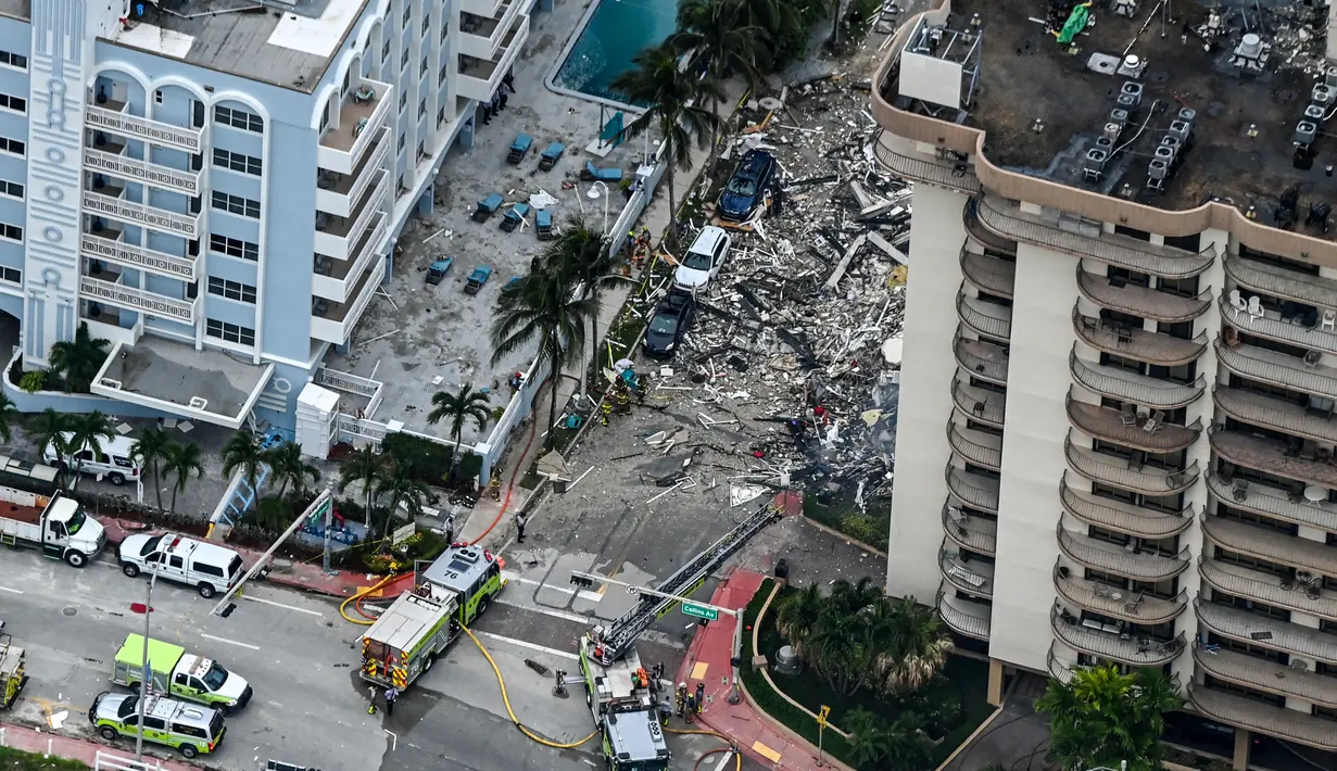 Pemandangan udara ini, menunjukkan tim penyelamat dan pencarian berada di lokasi runtuhnya sebagian menara apartemen tepi laut di Surfside, utara Miami, Kamis (24/6/2021). Tim tanggap menggunakan anjing dan drone terlatih untuk mencari korban selamat. (CHANDAN KHANNA/AFP)