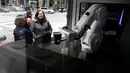 Pelanggan menyaksikan robot barista membuat kopi di Cafe X, San Francisco, California, AS, Selasa (12/2). Cafe X menggunakan robot untuk menyajikan makanan dan minuman. (Justin Sullivan/Getty Images/AFP)