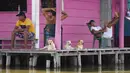 Sejumlah pria dan anjing beristirahat di teras rumah di Cienaga Grande de Santa Marta, Nueva Venecia, Kolombia, 12 Oktober 2021. Sekitar 400 keluarga tinggal di rumah panggung di Cienaga Grande. (AP Photo/Fernando Vergara)