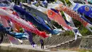 Seorang pria mengambil gambar koinobori, bendera berbentuk ikan koi, yang berkibar di atas Ngarai Kawakami, prefektur Saga, 13 April 2018. Pengibaran koinobori untuk menyambut perayaan Hari Anak di Jepang pada 5 Mei. (AP Photo/Eugene Hoshiko)