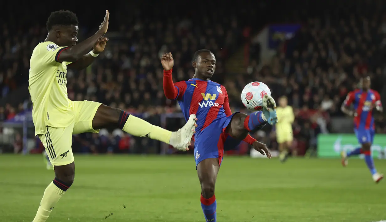 Gelandang Arsenal, Bukayo Saka berebut bola dengan pemain Crystal Palace, Tyrick Mitchell pada pertandingan Liga Inggris di stadion Selhurst Park di London, Inggris, Selasa (5/4/2022). Atas hasil ini, Arsenal tak berhasil melewati empat besar klasemen Liga Inggris. (AP Photo/Ian Walton)