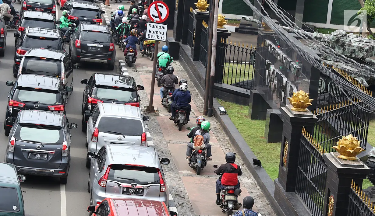 Pengendara sepeda motor melintasi jalur pejalan kaki di Jalan Medan Merdeka Timur saat kemacetan imbas demo sopir taksi di depan Istana Negara, Jakarta, Rabu (14/2). (Liputan6.com/Immanuel Antonius)