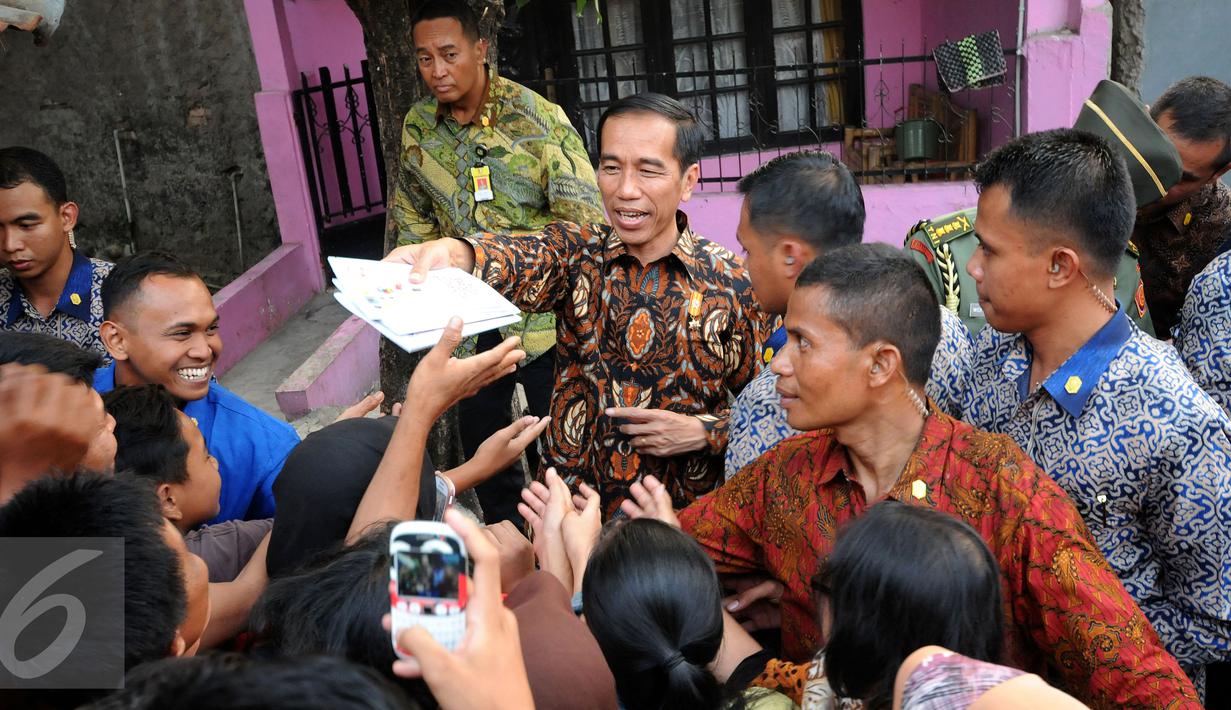 Presiden RI Joko Widodo membagikan buku tulis kepada warga di sekitar Lapangan Bedeng, Pisangan Baru, Jakarta, Selasa (8/9/2015). Kedatangan Presiden Jokowi untuk memberikan sejumlah paket sembako dan buku kepada warga. (Liputan6.com/Helmi Fithriansyah)