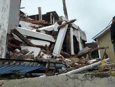 Penduduk desa memeriksa rumah mereka yang rusak setelah gempa magnitudo 5,1  di Sukabumi, Jawa Barat (10/3/2020). Menurut BMKG pusat gempa berada pada koordinat 6.81 LS dan 106.66 BT. (AFP/Handout/BNPB)