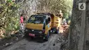Petugas menggunakan alat berat backhoe membersihan jalan dari longsoran tanah di RT 04/RW 03, Kademangan, Keranggan, Setu, Tangerang Selatan, Banten, Selasa (3/12/2019). Longsor pada Senin sore kemarin menewaskan seorang pengendara sepeda motor yang melintas, Anggi (23). (merdeka.com/Arie Basuki)