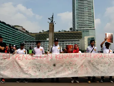 Sekelompok warga membentangkan Petisi Penolakan Kenaikan Tarif Dasar Listrik di kawasan Bundaran HI, Jakarta, Minggu (7/5). Mereka meminta pihak berwenang mengkaji kembali kebijakan kenaikan tarif dasar listrik. (Liputan6.com/Helmi Fithriansyah)