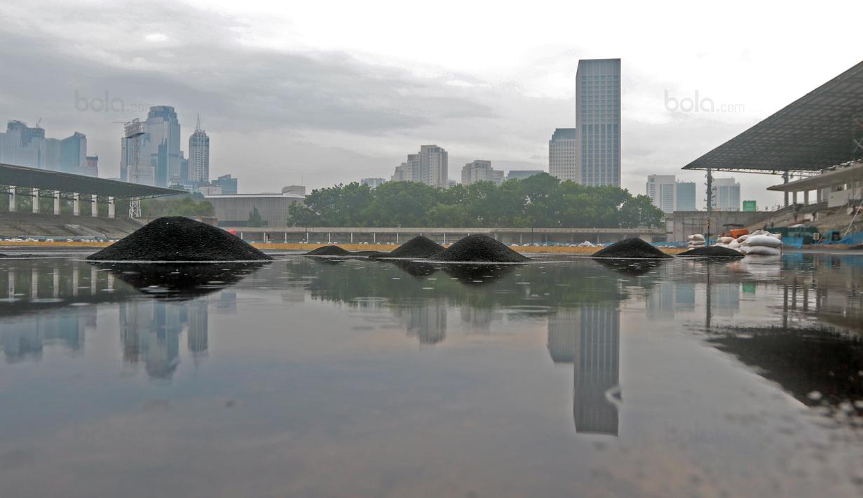 Suasana saat hujan menerpa tumpukan biji karet pada venue Atletik Stadion Madya di Kawasan Senayan Sport Center, Jakarta (12/10/2017). Venue Stadion Madya dalam tahap renovasi menyambut Asian Games 2018. (Bola.com/Nicklas Hanoatubun)