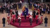 Cucu Ratu Elizabeth II (searah jarum jam dari tengah depan) Pangeran William, Peter Phillips, James, Viscount Severn, Putri Eugenie, Pangeran Harry, Putri Beatrice, Lady Louise Windsor dan Zara Tindall berjaga di sekitar peti jenazah Ratu Elizabeth II di Westminster Hall, di Istana Westminster, London, Sabtu (17/9/2022). Pangeran William berdiri di kepala peti mati Ratu bersama saudaranya di ujung yang berlawanan. (Yui Mok / POOL / AFP)