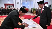 Tumpak Hatorangan Panggabean (kiri) menandatangani nota pelantikan sebagai Dewan Pengawas KPK disaksikan Presiden Joko Widodo di Istana Negara, Jakarta, Jumat (20/12/2019). Upacara pelantikan Dewan Pengawas KPK dipimpin langsung Presiden Joko Widodo. (Foto: Biro Pers Setpres)