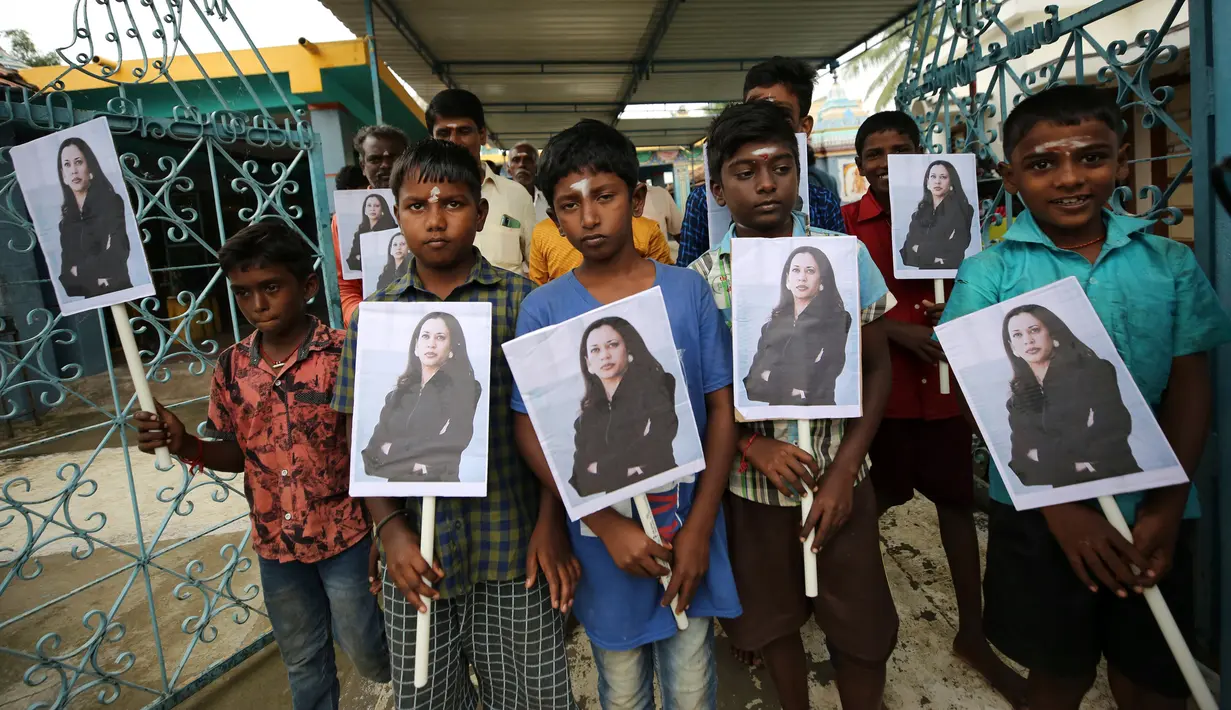 Anak-anak desa memegang plakat bergambar Wakil Presiden AS terpilih Kamala Harris usai berpartisipasi dalam doa khusus menjelang pelantikan Harris di luar sebuah kuil Hindu di Thulasendrapuram, selatan Chennai, Tamil Nadu, India, Rabu (20/1/2021). (AP Photo/Aijaz Rahi)