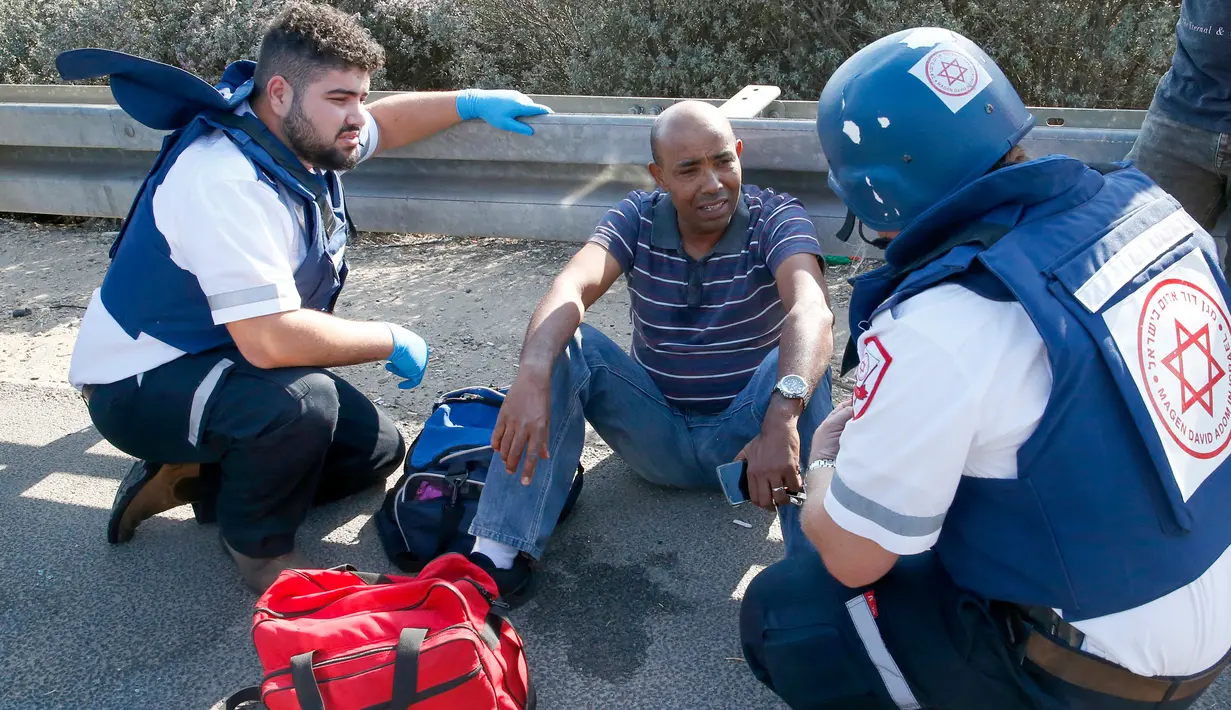Petugas medis berbicara dengan seorang pria yang terluka dalam serangan roket dari Jalur Gaza di Kota Ashdod, Israel, Selasa (12/11/2019). Tewasnya komandan Jihad Islam Baha Abu Al-Ata memicu serangan balasan dari militan Palestina di Gaza. (Jack Guez/AFP)