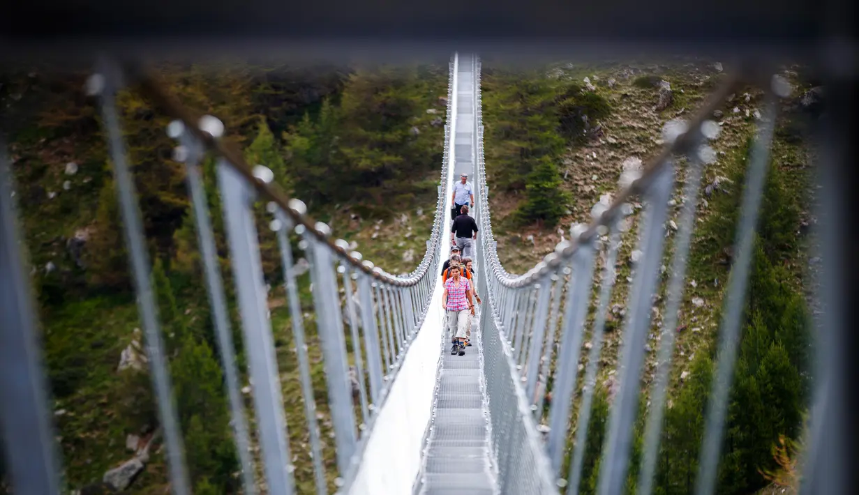Wisatawan berjalan di atas jembatan gantung yang baru diresmikan di Kota Zermatt, Swiss, 29 Juli 2017. Jembatan baru ini disebut memiliki berat sekitar delapan ton, dan dilengkapi dengan sistem untuk mencegah goyangan. (Valentin Flauraud/Keystone via AP)