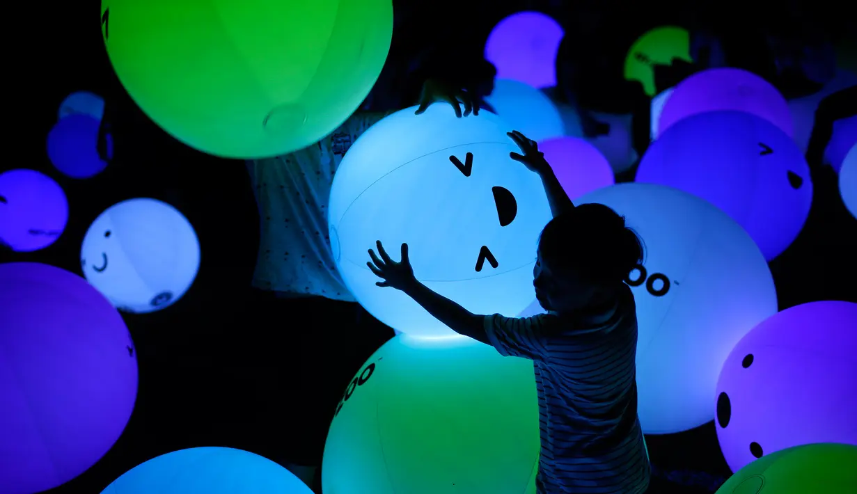 Siluet seorang anak yang sedang bermain balon berbagai warna saat festival Light Marina Bay di Singapura (8/3). Seni instalasi ini dirancang dengan pencahayaan ramah lingkungan yang hemat energi. (AP Photo / Wong Maye-E)