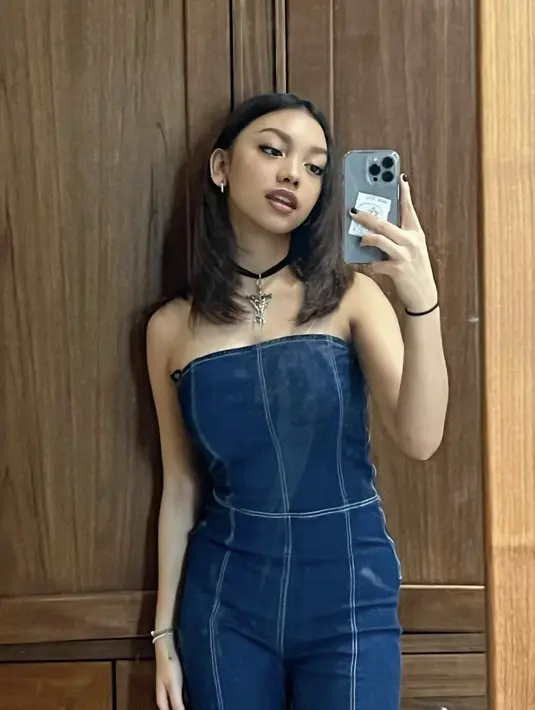 Ia juga tampak menggemaskan dengan jumpsuit denim disertai kalung choker. OOTD-nya berhasil membawa nostalgia gaya tahun 90-an. [Foto: Instagram/nauraayu]