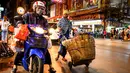 Seorang pengantar barang mendorong gerobaknya di sebuah jalan di Chinatown Bangkok (16/9/2020). Di Chinatown Bangkok terdapat juga beberapa kuil penting, salah satunya Wat Traimit yang ada di ujung jalan Yao Warat. (AFP/Mladen Antonov)