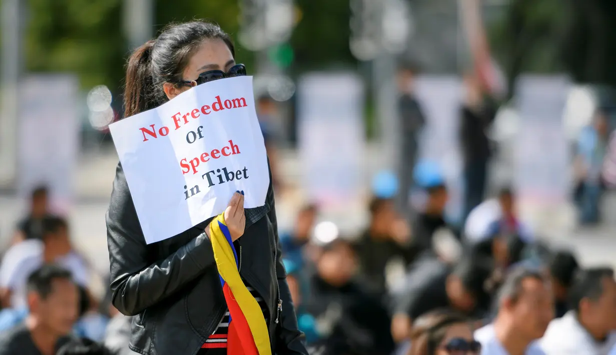 Seorang pengunjuk rasa membawa sebuah kertas bertuliskan "Tidak ada kebebasan bicara di Tibet" Jenewa, Jumat (16/9). Pengunjuk rasa meminta Presiden Tiongkok, Xi Jinping untuk menghentikan pembunuhan di Tibet. (AFP PHOTO/Fabrice Coffrini)